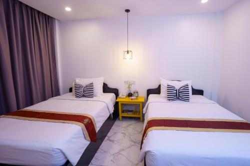 a room with two beds and a yellow table at The Rabbit Hole Hotel & SPA in Siem Reap