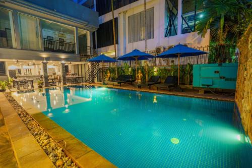 a large swimming pool in a building with blue umbrellas at The Rabbit Hole Hotel & SPA in Siem Reap