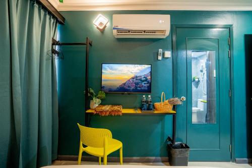 a blue room with a table and a yellow chair at Hotel 28 Chow Kit Kuala Lumpur in Kuala Lumpur