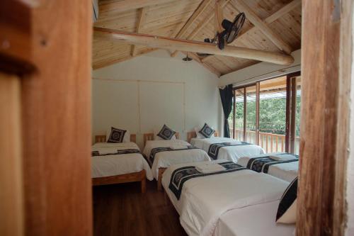 een rij van vier bedden in een kamer met houten plafonds bij Bong Bang homestay 2 in Na Hang