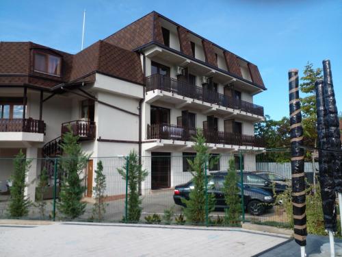 a building with a car parked in front of it at Pensiunea Duet in Sărata-Monteoru