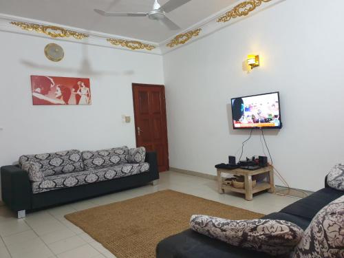 sala de estar con 2 sofás y TV de pantalla plana en Globe-trotter vision B en Cotonú