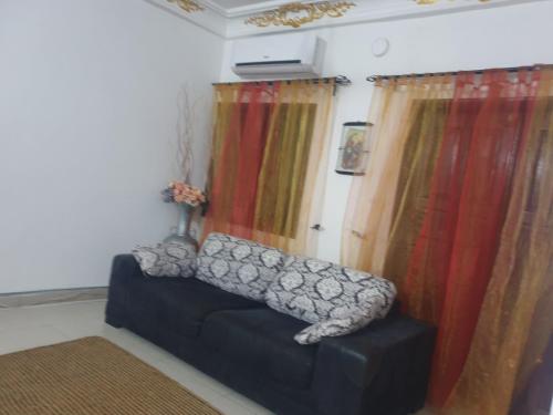a living room with curtains and a black couch at Globe-trotter vision B in Cotonou