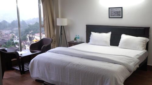 a bedroom with a bed and a desk and a window at The Relyn Suite in Shillong