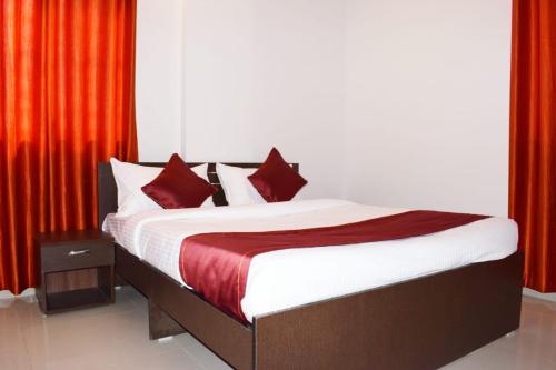 a bedroom with a bed with red curtains at Hotel Sayee luxury Inn in Pune