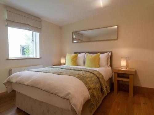 a bedroom with a bed with yellow pillows and a mirror at Coot Lodge in Somerford Keynes