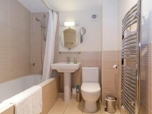 a bathroom with a toilet and a sink and a bath tub at Coot Lodge in Somerford Keynes