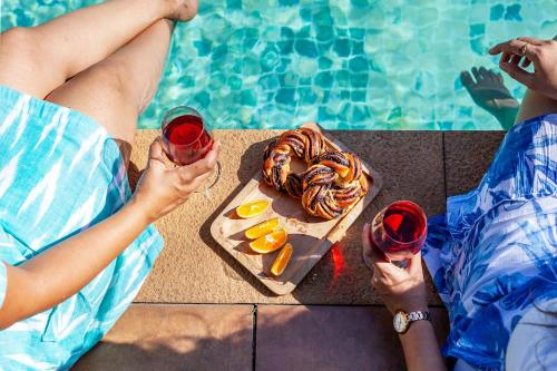 two people holding wine glasses and a plate of food at StayVista Bella Antlia 3BHK, with Pvt Pool & Paddy view- Parra, North Goa in Anjuna