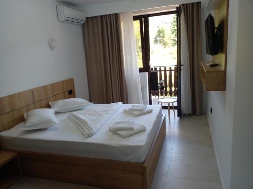 a bedroom with a bed with white sheets and a balcony at Pensiunea Duet in Sărata-Monteoru