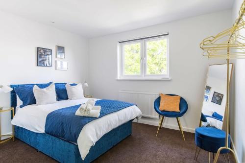 een slaapkamer met een blauw bed en een blauwe stoel bij LiveStay-4 Bed London Townhouse, Private Terrace, Parking in Brentford