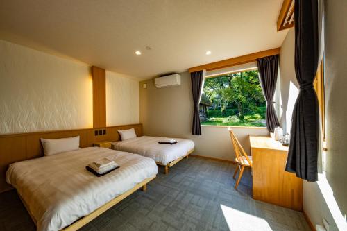 a hotel room with two beds and a window at CURIO Shirakawago in Shirakawa