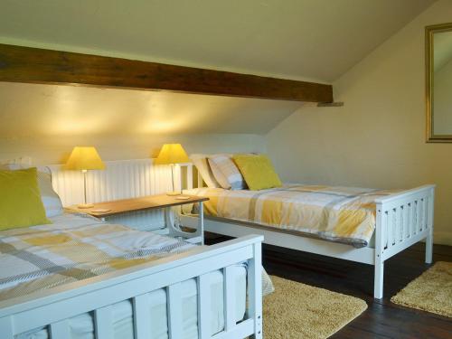 1 dormitorio con 2 camas, mesa y lámparas en Courtyard Cottage At Dam Hall Barn, en Peak Forest