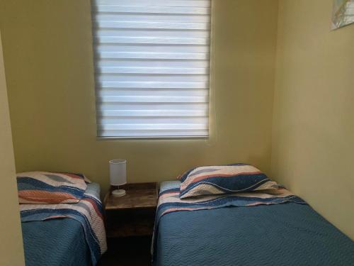 two beds in a small room with a window at Amplio Depto en Viña del Mar con Estacionamiento. in Viña del Mar