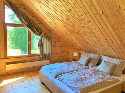 a bed in a room with a wooden ceiling at Chata Green in Veľká Lomnica