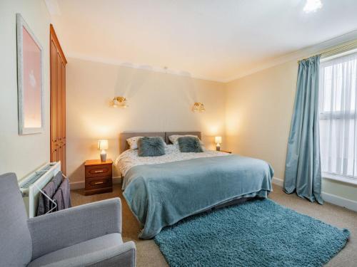 a bedroom with a bed with a blue blanket and a chair at West End Farm Lodge in Burton Agnes