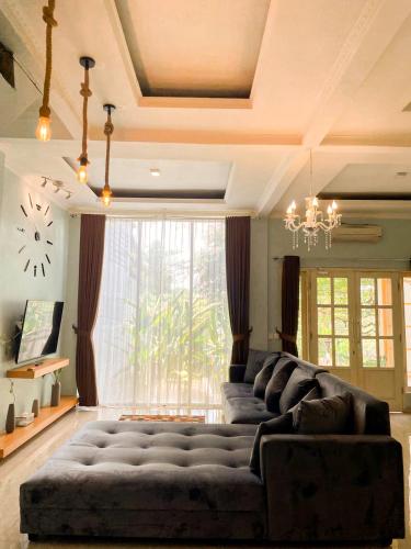a living room with a large couch in front of a window at Villa Kamar Tamu Warungboto in Yogyakarta