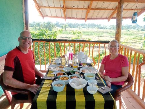 a man and woman sitting at a table with food at Ridge Boundary View in Dambulla