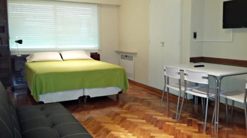 um quarto com uma cama, uma mesa e uma televisão em Studio Maipu em Buenos Aires