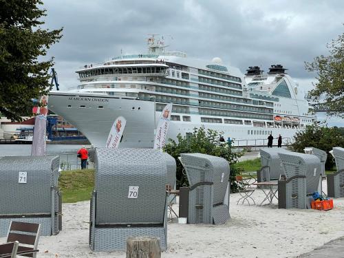 a cruise ship is docked at a beach with chairs at Kanal-Haus "Das Gästehaus direkt am NOK" in Osterrönfeld