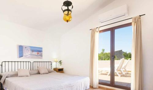 Dormitorio blanco con cama y puerta corredera de cristal en BeOnHolidays Villa Sa Fonera, en Maria de la Salut