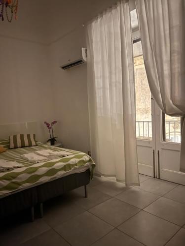 a bedroom with a bed and a large window at CiuriCiuri Home Appartamento storico nel centro di Catania in Catania