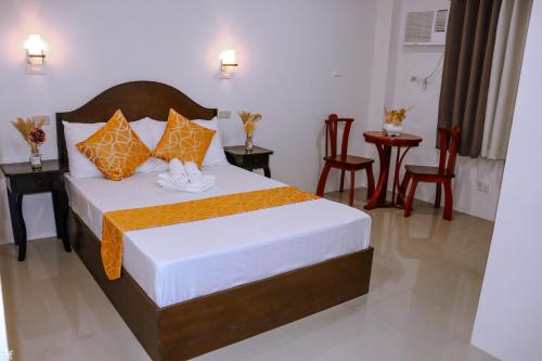 1 dormitorio con 1 cama con almohadas de color naranja y blanco en Dianna’s Inn en Corón