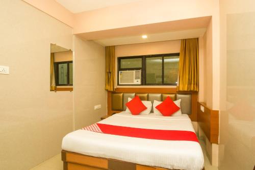 ein Schlafzimmer mit einem Bett mit roten Kissen in der Unterkunft OYO Hotel Sarovar Grand in Kalamboli