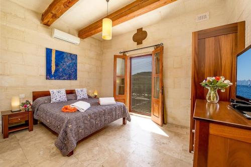 Hamlet 1 Holiday Home في Għasri: غرفة نوم بسرير وتلفزيون وطاولة