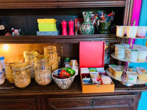una mensola con barattoli di cibo e altri prodotti di Aux couleurs de Commarin CHAMBRES d'hôtes a Commarin