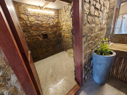 a stone walled bathroom with a door and a plant at Deshadan Eco Valley Resort - An Eco friendly Mud House in Kanthalloor