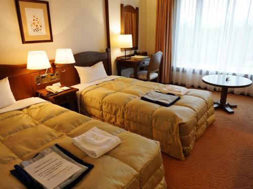 a hotel room with two beds and a table at Hotel Onikoube in Osaki