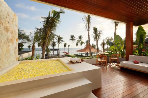 a bath tub with a view of the ocean and palm trees at Amarta Beach Retreat by Nakula in Tabanan