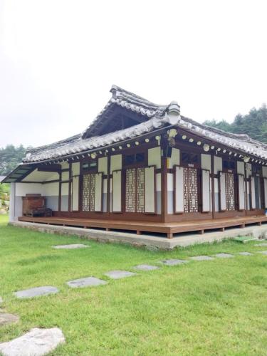 a building with an asian roof in a field at Hakdong Hanok Pension in Gangneung