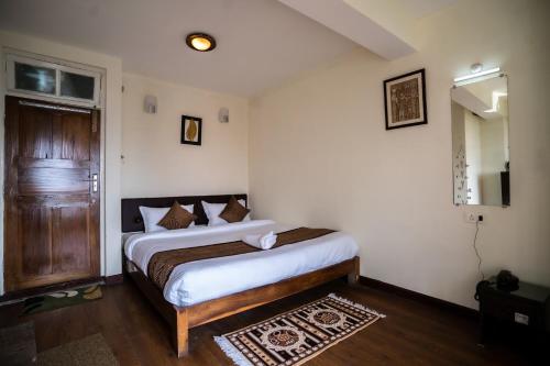 Schlafzimmer mit einem Bett, einem Spiegel und einer Tür in der Unterkunft THE GOLDEN LEAF in Darjeeling
