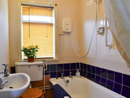 uma casa de banho com uma banheira, um lavatório e um WC. em Avenel Cottage em Town Yetholm