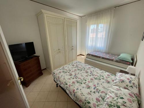 a bedroom with a bed and a cabinet and a television at Appartamento Note d’estate in Marina dʼAndora
