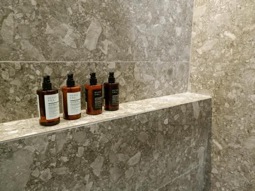 three bottles of essential oils sitting on a shelf in a bathroom at Kaiser Luxury Suites in Achílleion