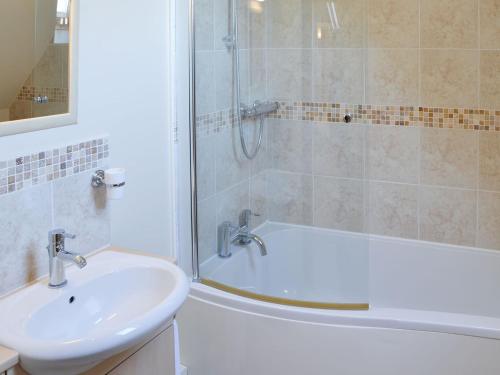 a bathroom with a sink and a shower and a tub at Teasel in Stalham