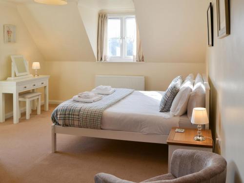 a bedroom with a bed and a desk and a window at Teasel in Stalham