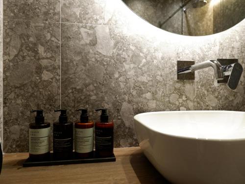 Baño con 3 botellas de champú en un estante junto a un fregadero en Kaiser Luxury Suites en Achílleion