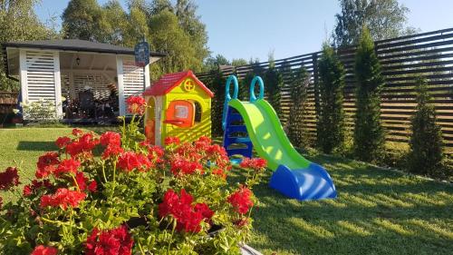 a garden with a play set and some flowers at Biały Domek koło Żywca in Pewel Wielka