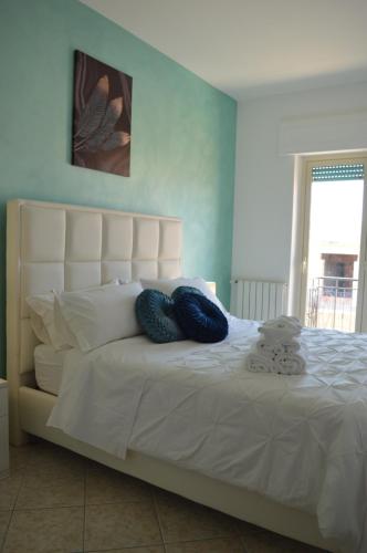 duże białe łóżko z 2 niebieskimi poduszkami w obiekcie Emerella Guest House Siderno Beach w mieście Siderno Marina