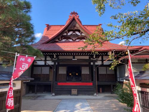 a building with a red roof and two flags at Temple Hotel Takayama Zenkoji in Takayama