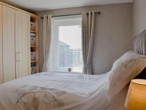 - une chambre avec un lit blanc et une fenêtre dans l'établissement Honeysuckle Cottage, à Springside