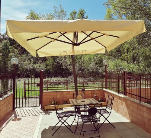 stół i krzesła pod parasolem na patio w obiekcie La Casa di Golia w mieście Bagni San Filippo