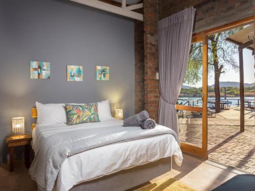 een slaapkamer met een bed en een groot raam bij Waschbank River Lodge in Gariepdam