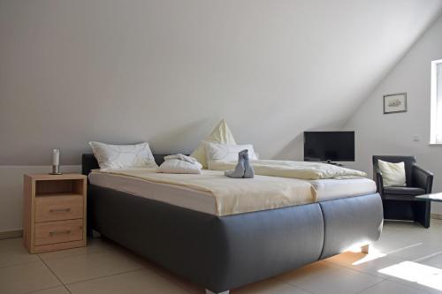a bedroom with a large bed and a chair at Wellness Appartements in Ihlowerfehn