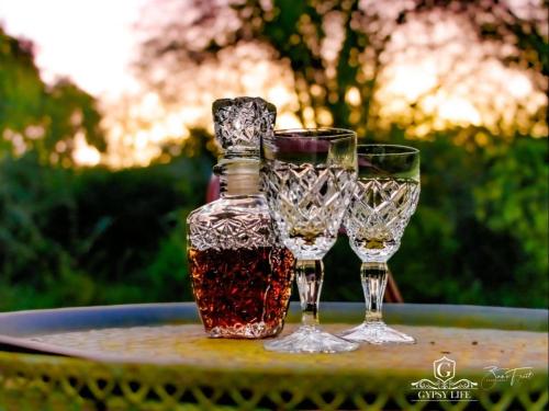 three wine glasses and a bottle on a table at Gypsy Wagons and Vans, Clarens in Clarens