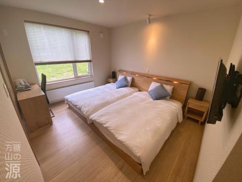 Schlafzimmer mit einem Bett mit weißer Bettwäsche und einem Fenster in der Unterkunft 山の源-Yama No Minamoto in Furano