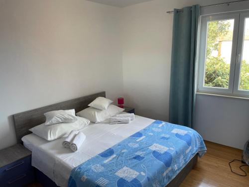 a bedroom with a bed with a blue comforter and a window at Apartments Dumina in Murter